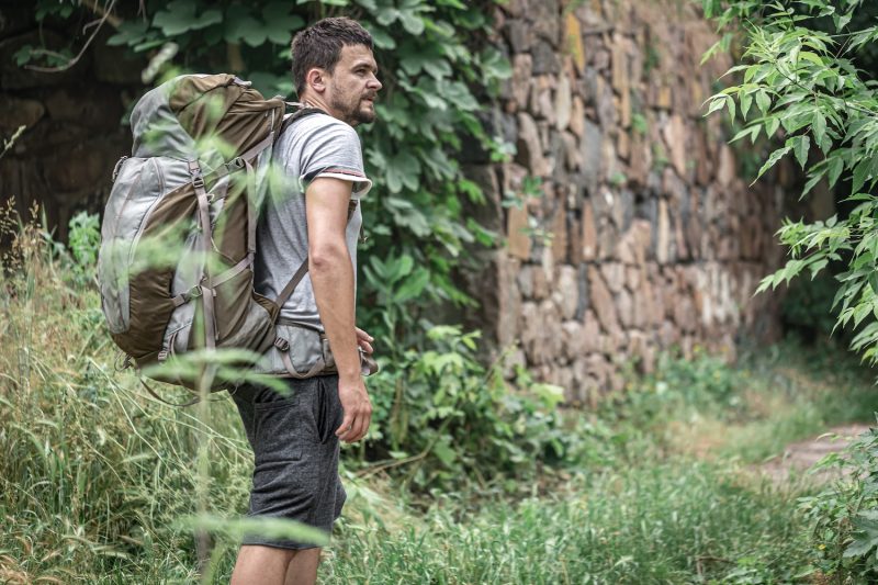A man on a hike with a large backpack travels in the forest.